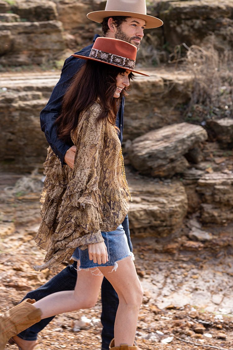 Two people walking together along the shoreline in a Lenny-Wool-Short-Brim-Hat-Rust