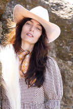Woman wearing a Flea Style Rider Ivory Western Hat and checkered dress against rocks.