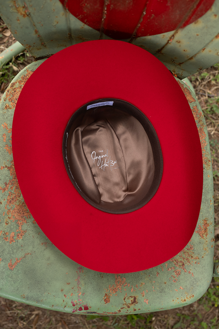 Red cowboy hat with Original Hat Bar brown lining on a rusty metal chair-Fleastyle