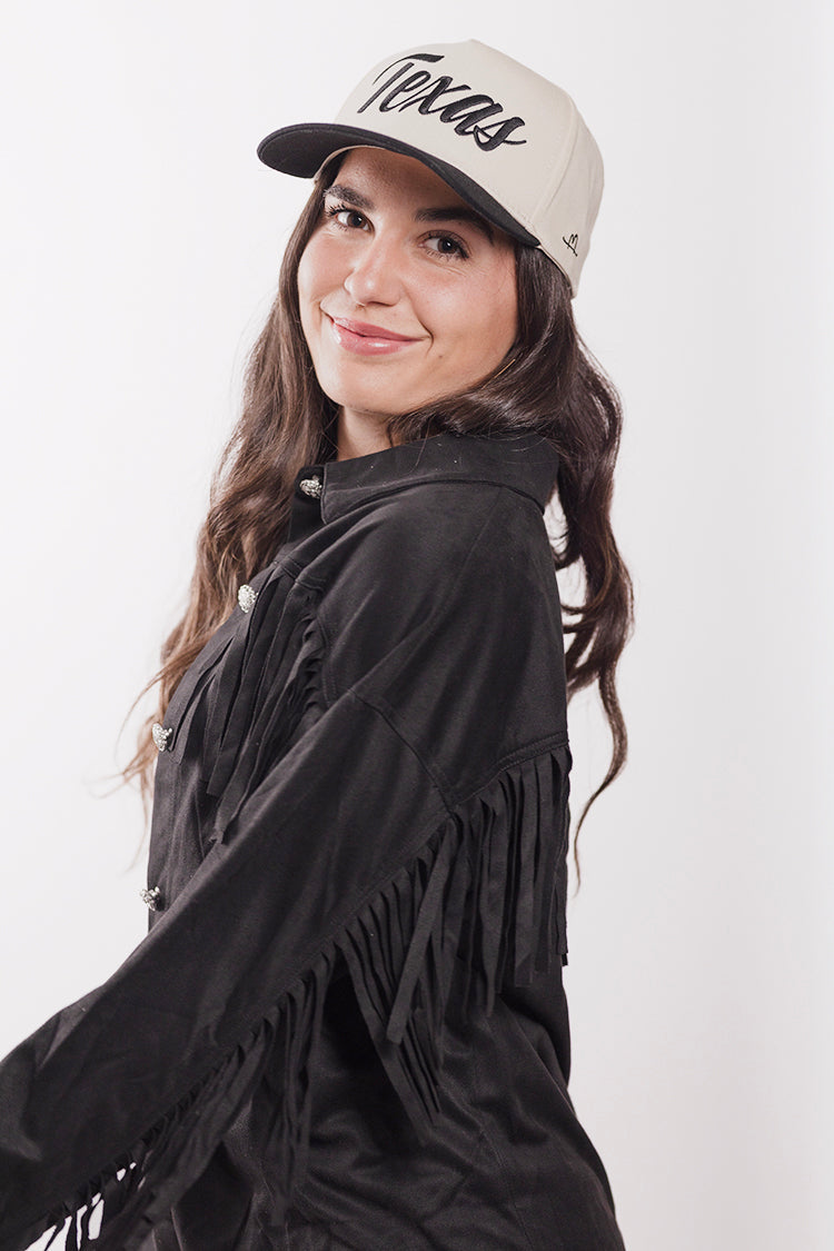 Woman wearing a black fringe jacket and black  'Texas' trucker hat-FleaStyle
